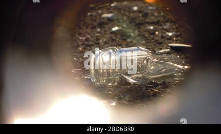 Broken glass bottles of beer and alcohol on the sidewalk. Urban pollution by glass. Environmental vandalism. Broken glass on asphalt. Stock Photo