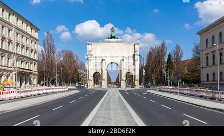 Panorama of Siegestor (victory gate). Rear view with empty Ludwigstraße in the foreground. With blue sky and white clouds. A landmark of Munich. Stock Photo
