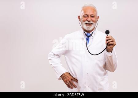Portrait of  senior doctor holding  stethoscope on gray background. Stock Photo