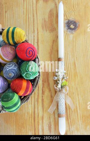 Basket with eggs decorated with threads and an Easter candle  on wooden  table Stock Photo