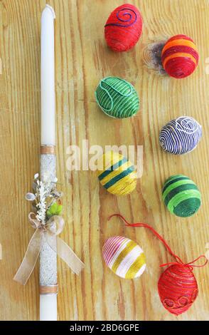 Eggs decorated with threads and an Easter candle  on wooden  table Stock Photo