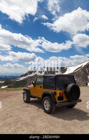 Shoshone National Forest, Wyoming, USA - July 13, 2014:  A gold Jeep Rubicon in a dirt parking area with the dynamic landscape of Shoshone National Fo