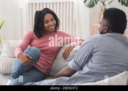 Married black couple chatting and resting on couch at home Stock Photo