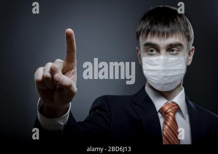 concept coronavirus epidemic, businessman in medical mask on face, finger point touches Stock Photo
