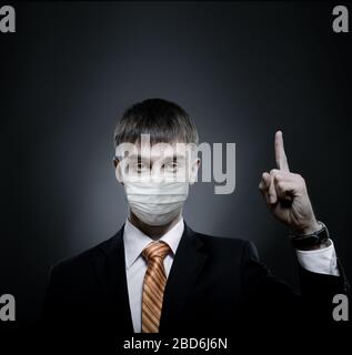 concept coronavirus epidemic, portrait businessman in medical mask, black costume and orange necktie, face closeup Stock Photo