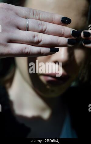 Young woman hiding her eyes with the hands. Not wanting to see or not wanting to be seen. Focus on the hands. Stock Photo