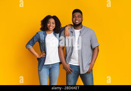 Cool Millennials. Attractive young black couple posing together over yellow background Stock Photo