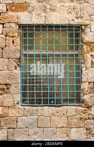 Barred window in the old collapsing wall of the building Stock Photo