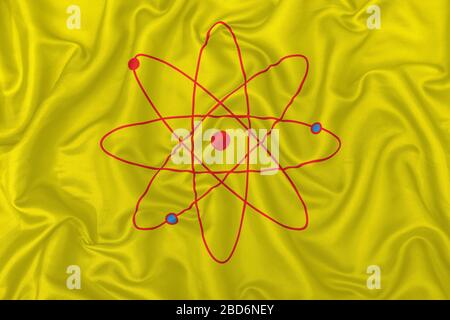 Atom sign symbol isolated in a yellow silk satin fabric texture. Stock Photo