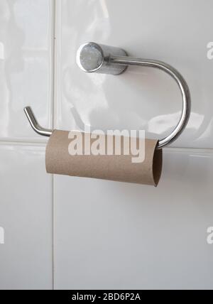 Empty toilet roll on holder in a white tiled bathroom.  Stock Photo