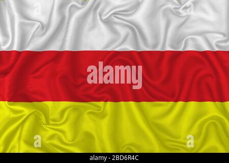North Ossetia–Alania flag on wavy silk textile fabric background. Stock Photo