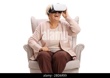 Senior woman sitting in an armchair and using a VR headseat isolated on white background Stock Photo