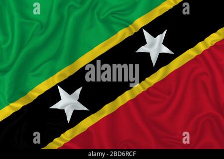 Saint Kitts and Nevis country flag on wavy silk textile fabric background. Stock Photo