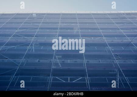 High building in Scaffolding against blue sky, construction works at building site, restoration new complex Stock Photo