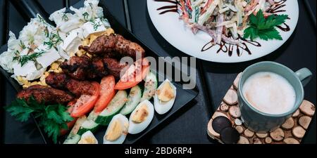 Delicious not mixed Cobb salad with fried BBQ meat served on the original shovel shaped melamine plate in the restaurant. Cold dish and coffee. Stock Photo