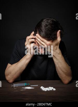Man drug addict calls on the phone for help, a pose of desperation. Stock Photo