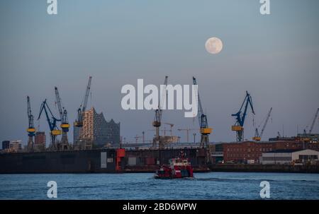 Hamburg, Germany. 07th Apr, 2020. The moon rises as a so-called supermoon, in the foreground the Elbphilharmonie can be seen. The moon reaches its perigee, i.e. the point closest to the Earth's orbit, as a full moon in the night of April 7-8 and therefore appears particularly large to the human observer. Credit: Daniel Reinhardt/dpa/Alamy Live News Stock Photo