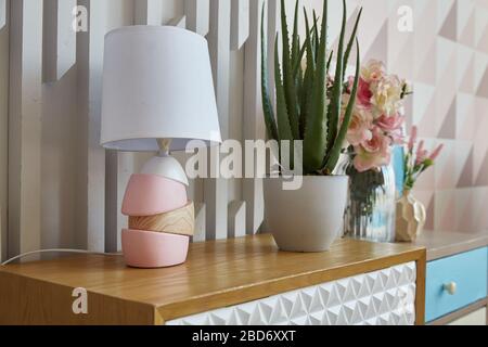 living room. lamp and flower potted on a chest of drawers in the room. Interior decoration. Stock Photo