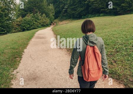 Female hiker walking on footpath outdoors, rear view of woman hiking in morning Stock Photo