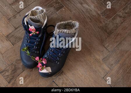 Three pair of legs in boots for hiking stand on the grey pavement. Top view of the feet in shoes for tourism. Stock Photo