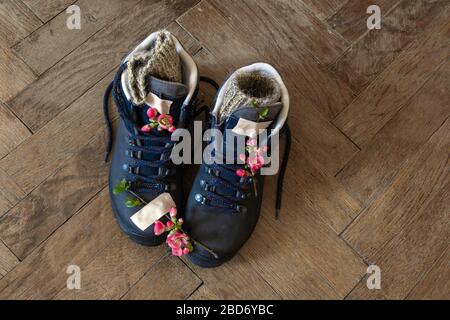 Three pair of legs in boots for hiking stand on the grey pavement. Top view of the feet in shoes for tourism. Stock Photo