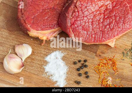 Top view on fresh raw beef fillet medallions with species on a wooden table. Stock Photo
