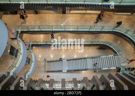 Melbourne Australia - March 9 2020; People on escalator surrounded by monochromatic patterns in architecture repeating long leading lines in interior Stock Photo