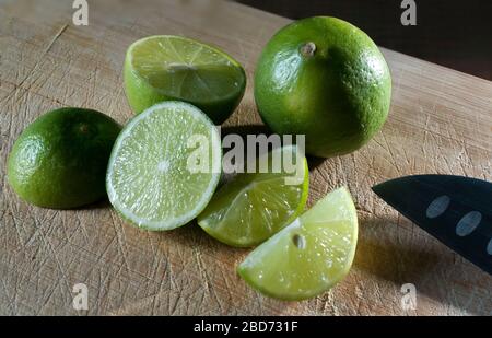 Lemon slices and a knife on the side, on an old cutting board with rim light on a lemon Stock Photo