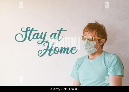 Stay at home during Covid-19 outbreak, man leaning on to wall of his living room looking out the window Stock Photo