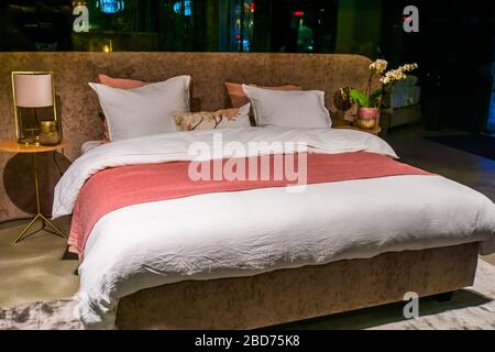 Modern double bed, luxurious bedroom interior, made bed with sheets and pillows Stock Photo