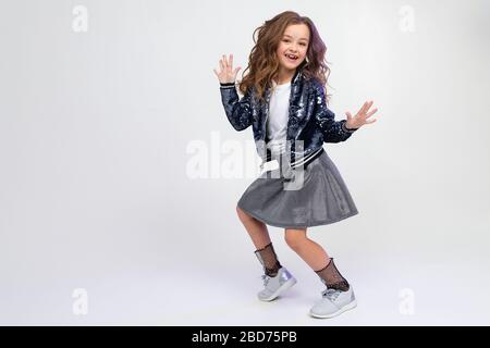 european teenager girl in a beautiful manner dancing in full growth on a light studio background with copy space Stock Photo