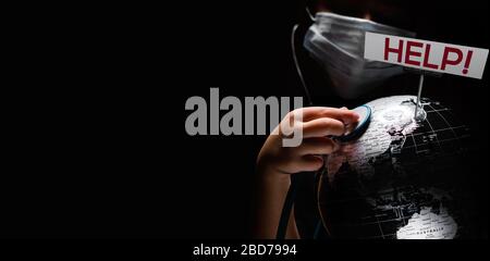 Kid hold globe put stethoscope on sphere where shown billboard Help red letters face covered in mask on black copy space background. Pandemic outbreak Stock Photo