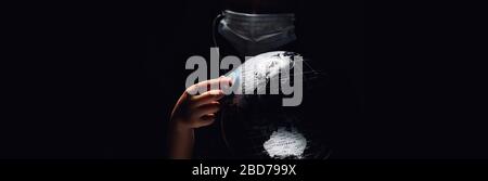 Kid hold globe put stethoscope on sphere, face covered in mask on black horizontal background. Ecological problems disasters. COVID-19 pandemic infect Stock Photo