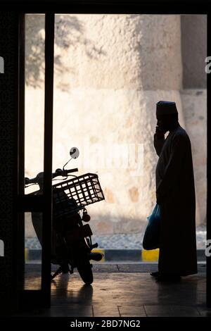 The silhouette of a man using his mobile phone in the souk of Nizwa, Oman Stock Photo