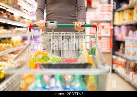 Woman pulling a shopping cart in a grocery store Stock Photo