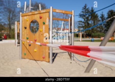 Empty playground without kids, closed to children and parents. Cut off with striped red white warning tape. Forbidden to entry by authorities. Restric Stock Photo