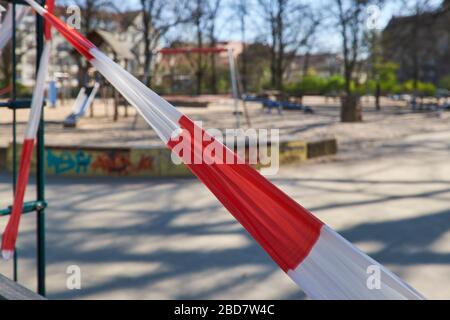 Empty playground without kids, off bound to children and parents. Closed off with striped red and white barrier tape. Forbidden to enter due to restri Stock Photo