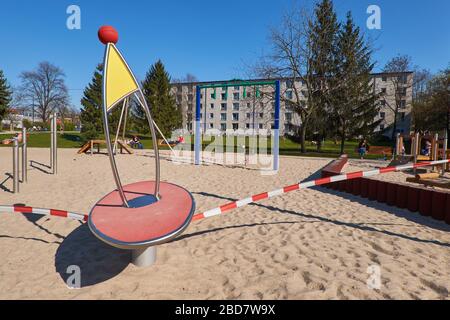 BERLIN, GERMANY - 6 April 2020: people gather around an empty playground without kids, off bound to children and parents. Closed off with striped red Stock Photo