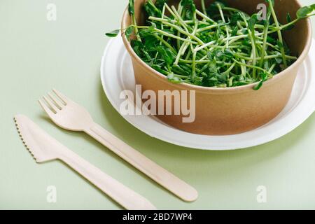 Close up shot of paper bowl full of pea sprouts and bamboo utensils Stock Photo