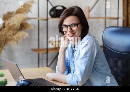 Working from home. Communication online. Portrait of smiling female freelancer using laptop Stock Photo