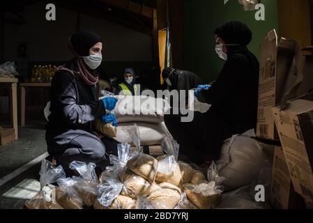 Baalbek, Lebanon, 7 April 2020. People pack food boxes, for 2000 Lebanese families struggling to make ends meet during financial crisis and the global coronavirus pandemic, at a sports hall converted into a food distribution center by Shia group, Hezbollah. Elizabeth Fitt Credit: Elizabeth Fitt/Alamy Live News Stock Photo