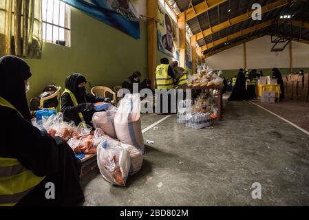 Baalbek, Lebanon, 7 April 2020. People pack food boxes, for 2000 Lebanese families struggling to make ends meet during financial crisis and the global coronavirus pandemic, at a sports hall converted into a food distribution center by Shia group, Hezbollah. Elizabeth Fitt Credit: Elizabeth Fitt/Alamy Live News Stock Photo