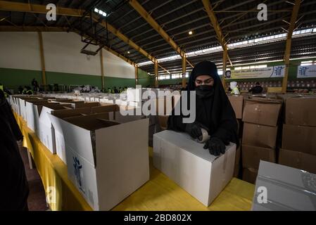 Baalbek, Lebanon, 7 April 2020. People pack food boxes, for 2000 Lebanese families struggling to make ends meet during financial crisis and the global coronavirus pandemic, at a sports hall converted into a food distribution center by Shia group, Hezbollah. Elizabeth Fitt Credit: Elizabeth Fitt/Alamy Live News Stock Photo