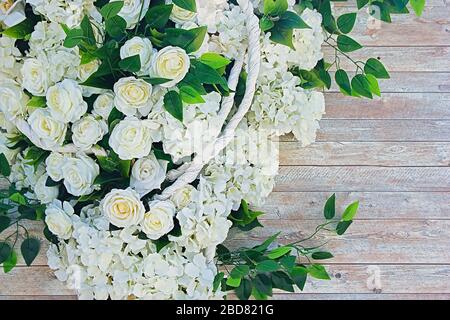 White flowers and green leaves on wooden background. Wedding background Stock Photo