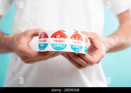 Man holding I vote today stickers roll with American flag Stock Photo