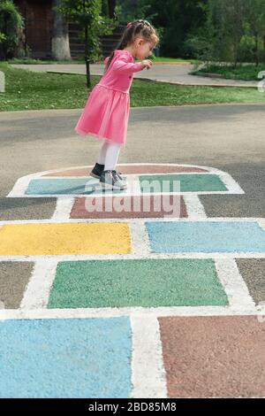 Young cute girl playing hopscotch on backyard Stock Photo