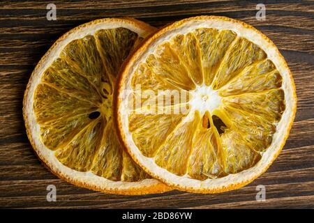 Dried oranges on a dark wooden table next to the jar. Close-up Stock Photo