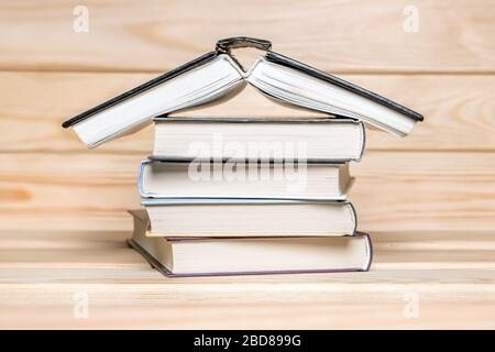 Stay at home concept. House made with books piled on wooden background. Stack of books. Education concept. Stack of books in form of a building. Book Stock Photo