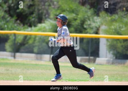 Little League baseball player running the bases with a big smile Stock Photo