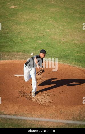 Teen baseball player in black and white uniform pitching Stock Photo